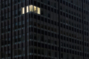 Corner office with lights on and windows glowing in a darkened o