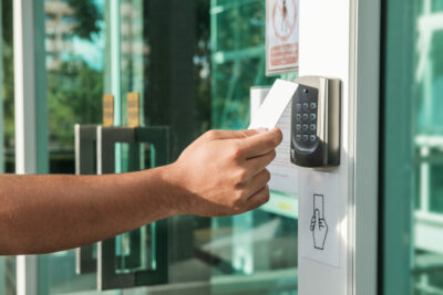 Hand using security key card scanning to open the door to enteri